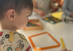 Chłopiec układa patyczki kolorowe