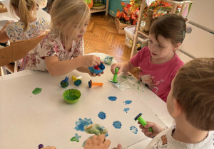Dziewczynki robią wzorki stemplami przy stolikach