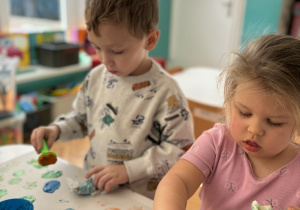 Dzieci robią stempelki na dużym kartonie