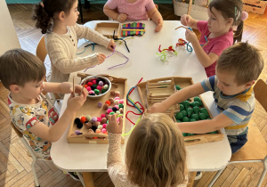 Dzieci przy stolikach z zestawami kreatywnymi