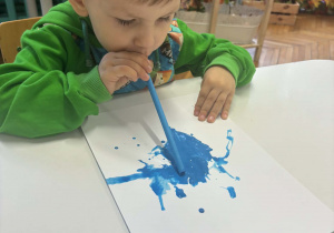 Chłopiec dmucha przez rurkę