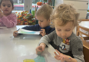 Dzieci przy stole rozsmarowują suche pastele