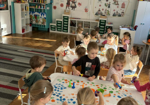 Dzieci przy stolikach bawią się kreatywnie