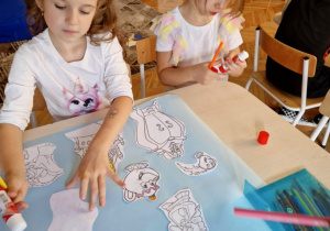 Dziewczynka przykleja sylwety z bajki Piękna i Bestia