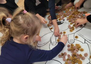 Dzieci wyklejają brzuch brązowymi puszkami