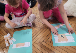 Dziewczynku ukladają puzzle z misiem