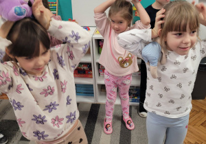 Dziewczynki pokazuja misie nad głową