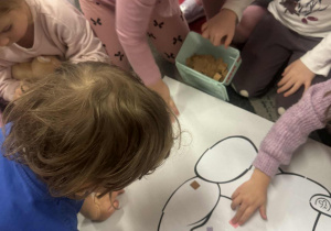 Dzieci wyklejają kolorowymi karotnikami misia