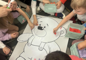 Dzieci najlejają kartoniki na misia