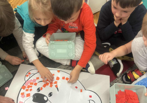 Dzieci naklejają na misie kolrowoe kartoniki