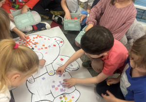 Dziec iwykelajają misia kolrowymi kartonikami