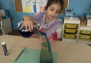 Dziewczynka wlewa wodę zabarwioną na niebiesko do oleju