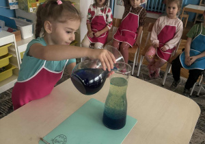 Dziewczynka wlewa niebieską wodę do oleju