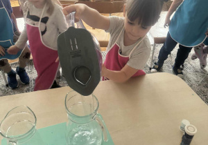 Dziewczynka wlewa wodę do dzbanka