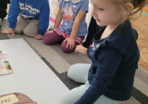 Dziewczynka kłądzie zdjęcie misia, na którym jest zły