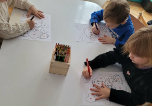 Dzieci siedza przy stole i kolorują