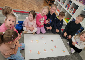 Grupa dzieci przed ilustracjami misia