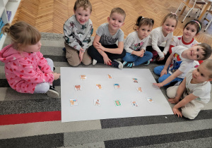 Dzieci siedzą na dywanie przed ilustracjami różnych misi