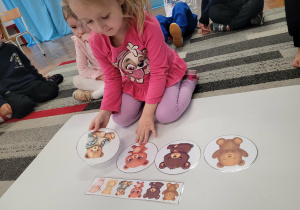 Dziewczynka uklada misia w kurtce