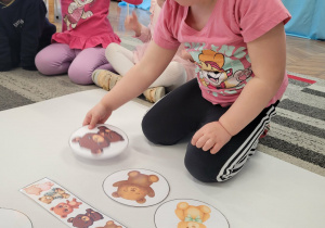 Dziewczynka kładzie ilustrację siedzącego misia