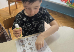 Chlopiec nakleja kartonik z misiem