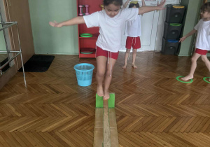 Dziewczynka idzie po ławeczce równoważnej