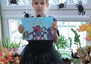 Dziewczynka przebrana za kota pokazuje obrazek andrzejkowy