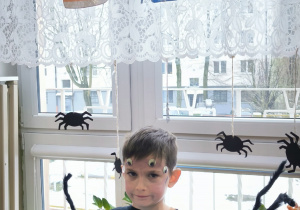 Chłopiec w przebraniu paja ka pokazuje obrazek andrzejkowy