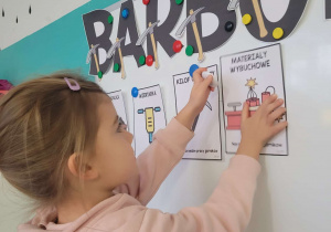 Dziewczynka przyczepia ilustrację dynamitu