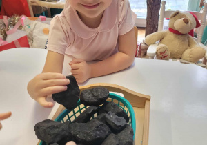 Dziewczynka dotyka bryły węgla