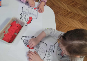 Dzieci przy stole wyklejają czapkę gónika