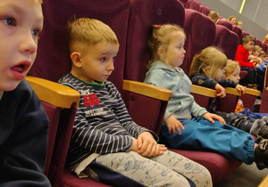 Dzieci siedzące na krzesłach w sali kinowej