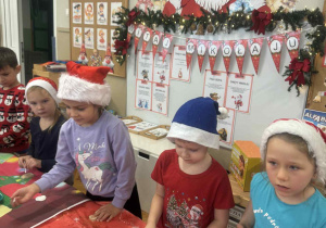 Dzieci smarują klejem ozdoby choinkowe