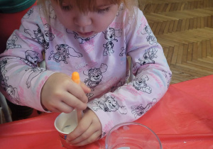 Dziewczynka barwi sól na pomarańczowo