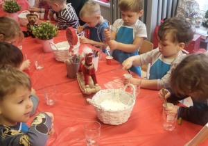 Dzieci mieszają sól siedząc przy stolikach