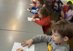 Dzieci przy stolikach rysują na kartkach aniołki