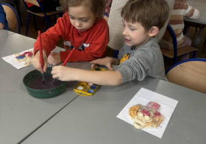 Chłopcy moczą pędzle w wodzie