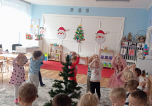 Dzieci pokazują rękoma czubek na choince