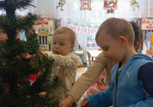 Chłopiec z dziewczynką zakładają bombki choinkowe