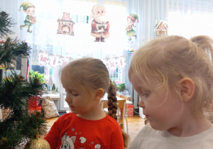 Dziewczynki zakładają złote bombki choinkowe