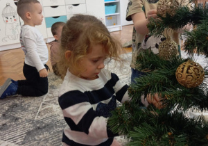 Dziewczynka z chłopcem zakładają bombki na choinkę