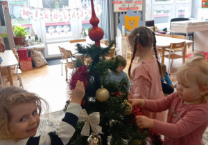 Dziewczynka zakłada czubek na choinkę