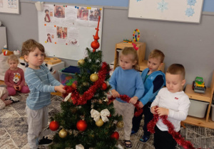 Dzieci trzymają czerwony łańcuch choinkowy