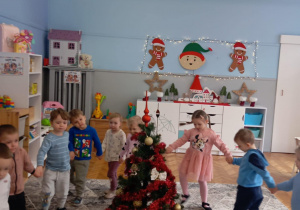 Dzieci robią koło wokół ubranej choinki