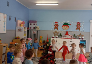 Dzieci idą po kole wokół ubranej choinki