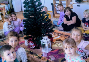 Dzieci siedzą przy choince