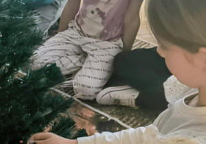 Dziewczynka przyczepia bombkę na choinkę