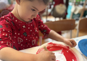 Dziewczynka maluje na czerono talerzyk