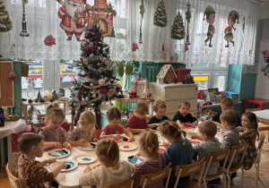 Dzieci siedza i wykonuja prace plastyczną