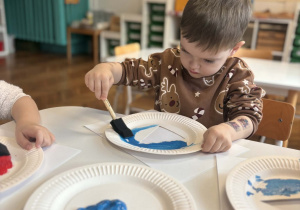 Chłopiec maluje talerzyk na niebiesko